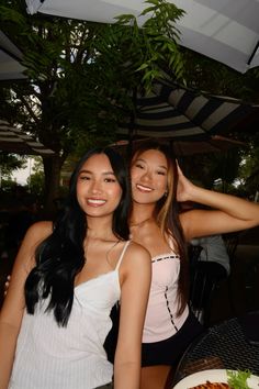 two beautiful young women standing next to each other in front of a plate of food