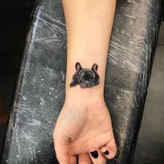 a small black dog tattoo on the wrist