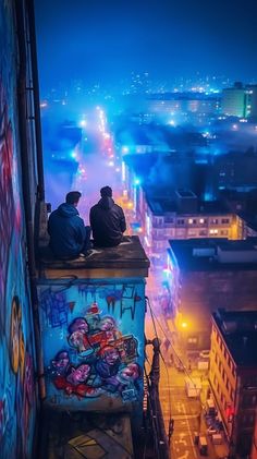 two people sitting on top of a tall building with graffiti painted on it's walls