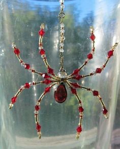 a glass jar with a spider hanging from it's side filled with red beads