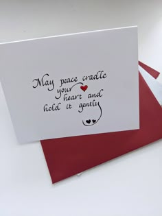 two red envelopes with white paper and black ink on them, one has a handwritten message that reads may peace oracle your heart and hold it gently