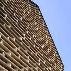 the side of a building that is made out of wooden slats and has holes in it