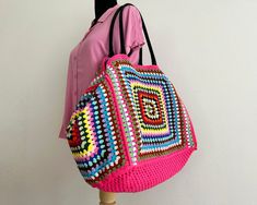 a pink crocheted bag hanging on a mannequin