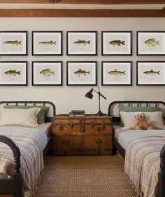 two twin beds in a room with pictures on the wall above them and a teddy bear