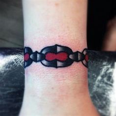 a tattoo on the wrist of a woman with a red heart and chain around it