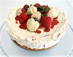 a white cake with strawberries and whipped cream on top is sitting on a glass plate