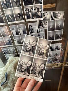 a person holding up some old black and white photos in front of a wall full of pictures