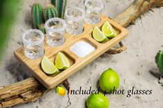 limes, salt and water are arranged on a wooden tray with cactus in the background