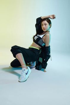 a woman in black and white is posing with her arms behind her back while wearing sneakers