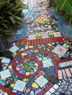 a man standing on top of a colorful mosaic floor next to green plants and trees