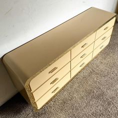 a tan and gold dresser sitting on top of a carpeted floor