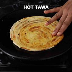 a hand reaching for a tortilla in a skillet