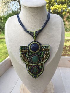 a beaded necklace on a mannequin with trees in the backgroud