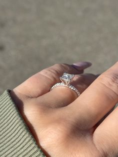 a woman's hand with a diamond ring on top of her finger and the other hand holding an engagement ring