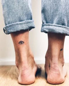 two people with small tattoos on their legs and feet, one has an eye tattoo