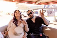 a man and woman sitting on top of a boat with their hands in the air