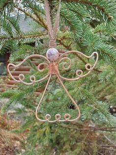 a metal angel ornament hanging from a tree