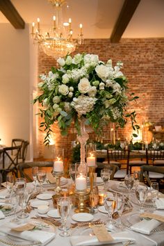 a centerpiece with white flowers and greenery on a table in a banquet hall