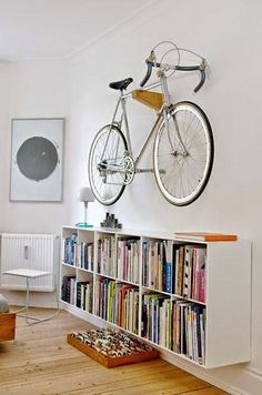 a bicycle mounted to the wall above a bookcase