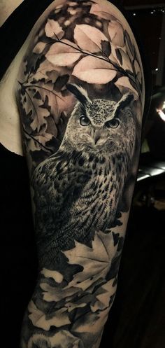 an owl and leaves tattoo on the arm