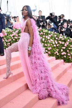 a woman in a pink gown standing on steps with her leg up and legs down