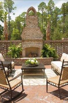 an outdoor living area with chairs, tables and a fire place in the middle of it