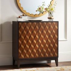 a wooden cabinet sitting in front of a mirror on top of a floor next to a vase with flowers