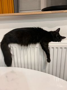 a black cat laying on top of a radiator