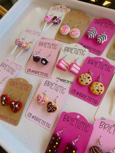 there are many different types of earrings on the table with price tags attached to them