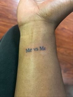 a person with a wrist tattoo that says me vs me on their left arm and the words