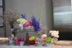 a table topped with lots of flowers on top of a white table covered in plates