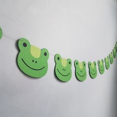 a green frog themed birthday banner hanging from a line with cutouts in the shape of frogs