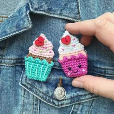 two small crocheted cupcakes are in the pocket of someone's jean jacket