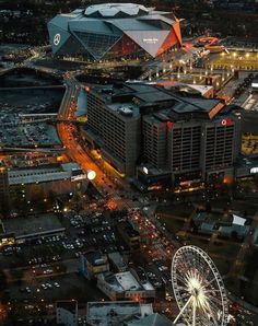 an aerial view of a city at night with the ferris wheel in the foreground