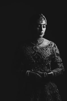 a black and white photo of a woman in an elaborate dress with pearls on her head