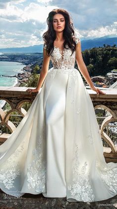 a woman in a wedding dress standing on a balcony with her hands on her hips