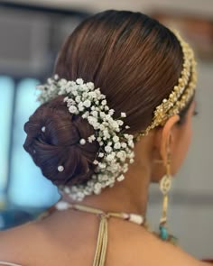 the back of a woman's head with flowers in her hair and pearls on it