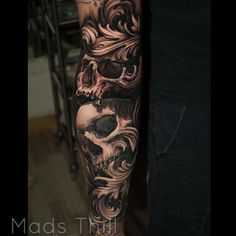 a man's arm with a skull and flowers on it