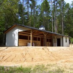 a small building sitting on top of a dirt field next to trees in the woods