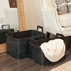 two black storage bins sitting on top of a wooden floor next to a white chair