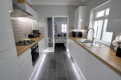 a narrow kitchen with tile flooring and white cabinets