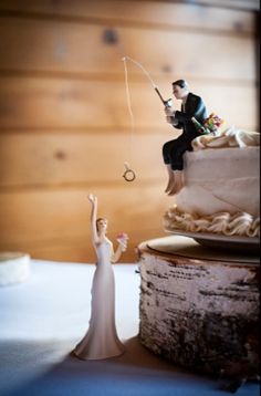 a wedding cake with a bride and groom fishing on the top, while another man is holding a fish rod