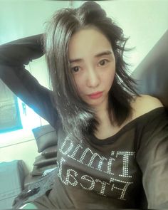 a woman with long black hair wearing a tshirt and posing for the camera