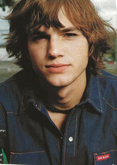 a close up of a person wearing a denim shirt and looking at the camera with a serious look on his face