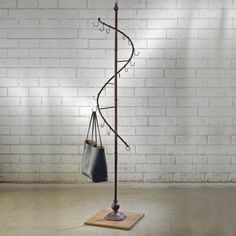 a coat rack with two purses hanging from it's sides in front of a brick wall