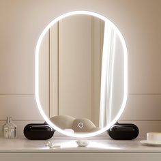 a round mirror sitting on top of a white table next to a cup and candle