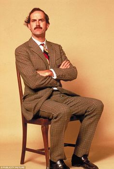 a man sitting in a chair with his arms crossed, wearing a suit and tie