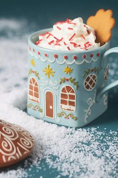 a cup filled with whipped cream sitting on top of a table next to a cookie