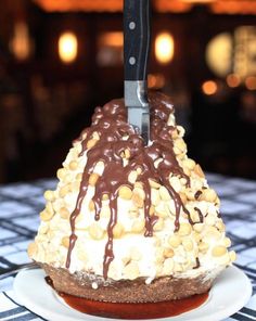 a knife sticking out of the top of a cake on a plate with chocolate sauce