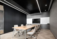 an empty conference room with white chairs and a wooden table in front of a black wall